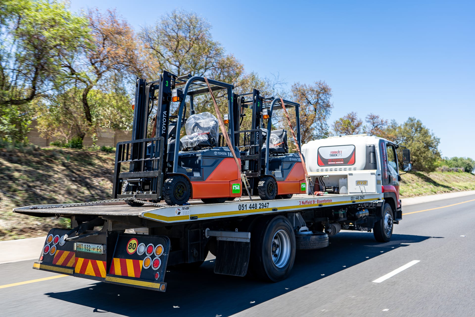 Two new Toyotas on a FTOFS delivery flatbed truck